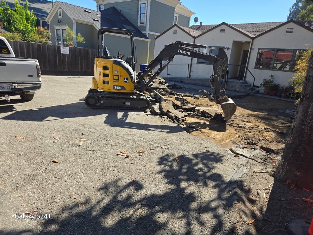 picture of an excavator excavating dirt in front of a home